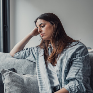 Sad young woman sitting on a couch.