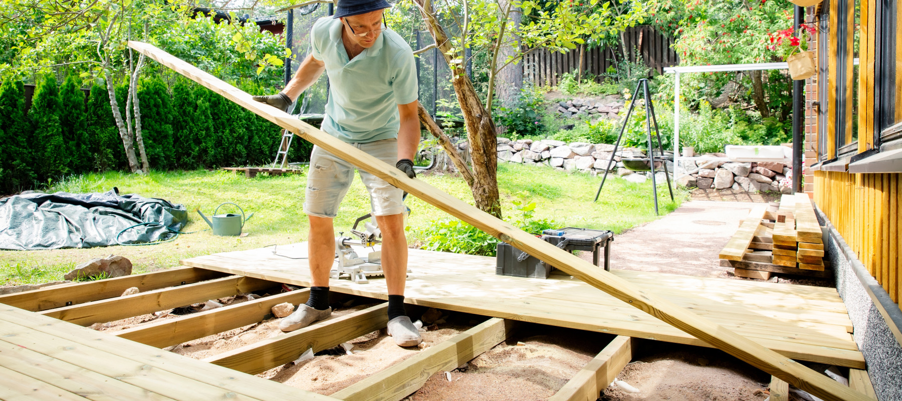 A man building a wooden deck in his backyard.