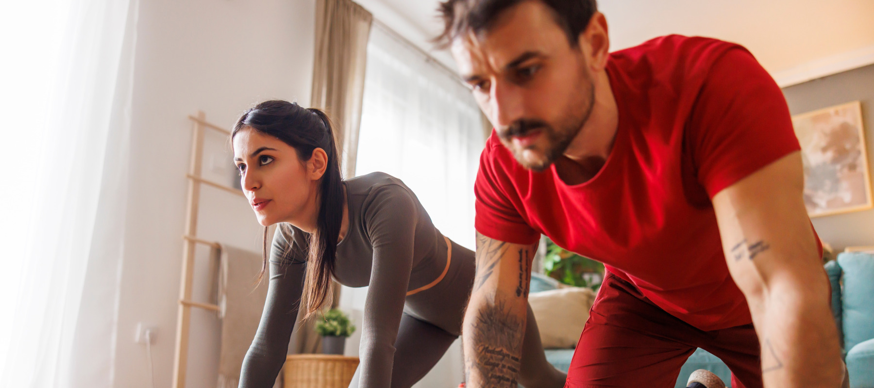 A man and a woman work out together in their home.