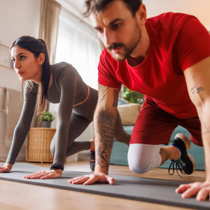 A man and a woman work out together in their home.