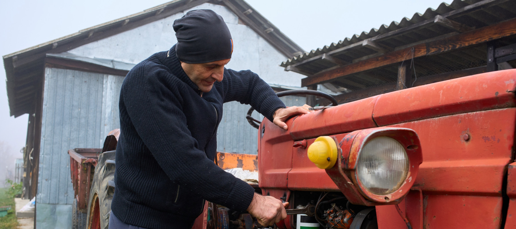 A farmer repairs aging harvesting equipment.