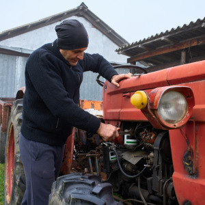 A farmer repairs aging harvesting equipment.