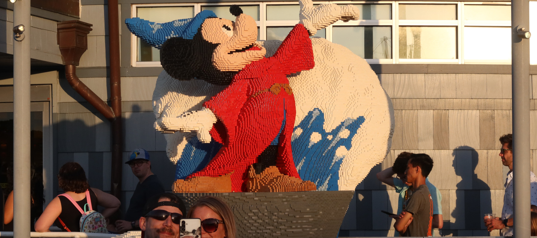 Visitors to Disney Springs take a selfie in front of a Fantasia Mickey statue made of Lego.