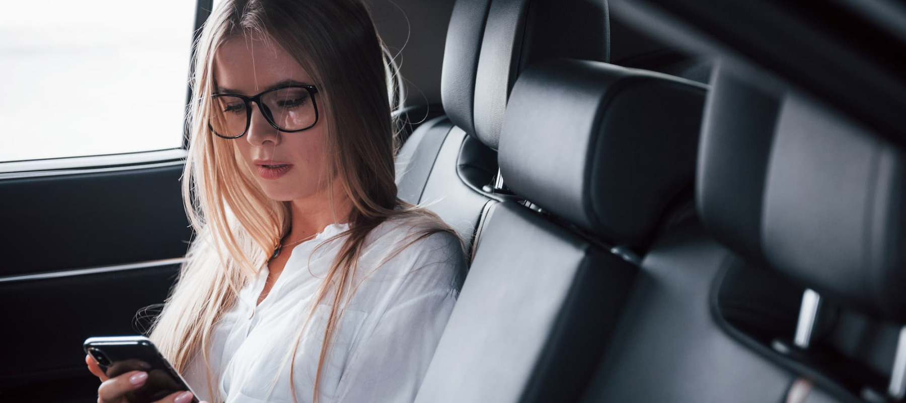 A photo of a woman sitting in the back seat of a car