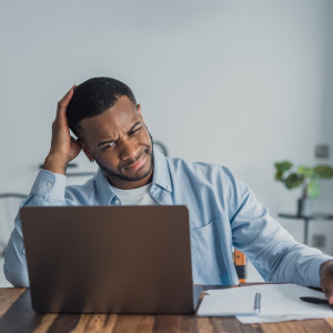 A photo of a man confused looking at his laptop