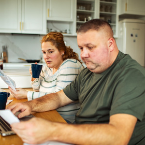 A concerned couple reviewing bills at home at their kitchen table.
