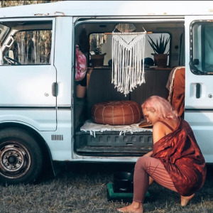 A photo of a woman cooking outside a campervan