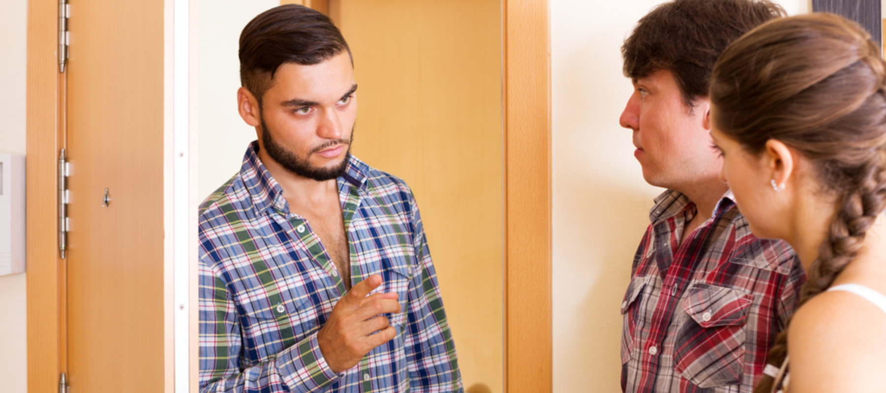 Photo of a man looking angrily at two tenants in his home