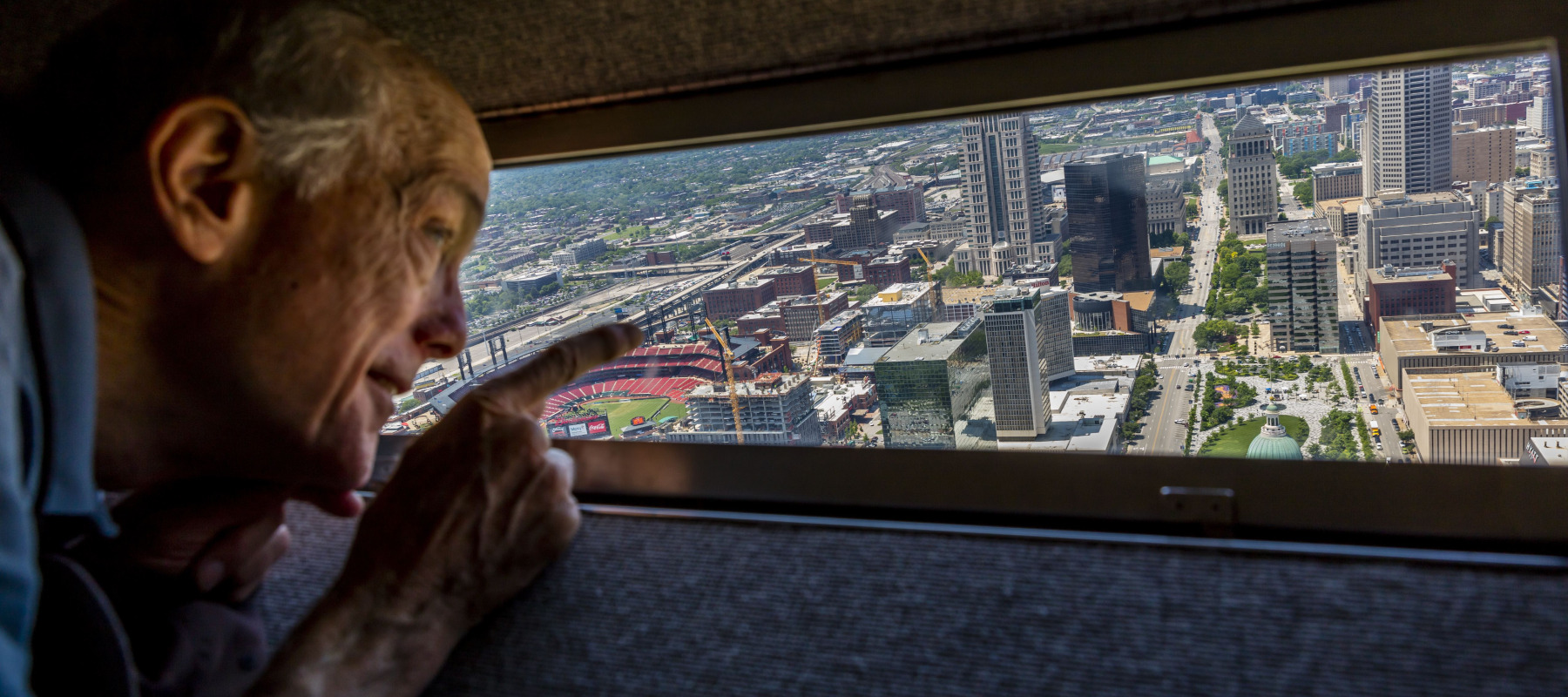 Man looks out window at top of Gateway Arch over St. Louis.