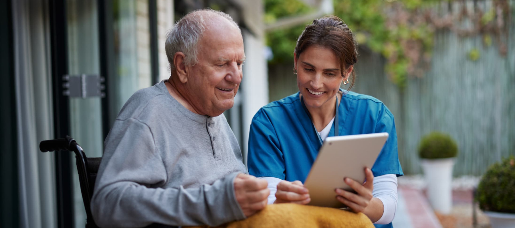 A photo of an elderly man at home with a nursing aid