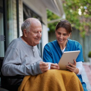 A photo of an elderly man at home with a nursing aid