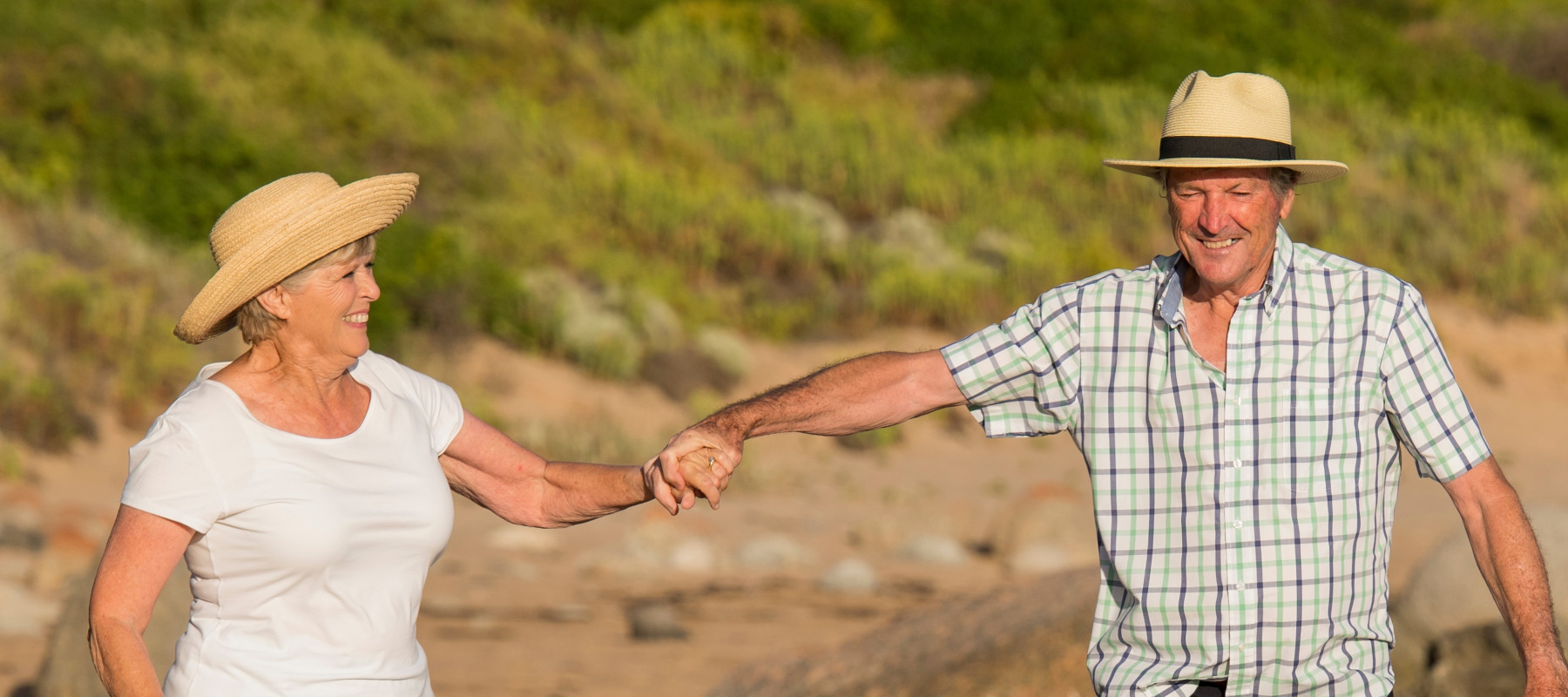 Older couple, retired and walking happily on the beach.