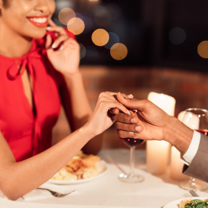A photo of a man holding a woman's hand at a fancy restaurant