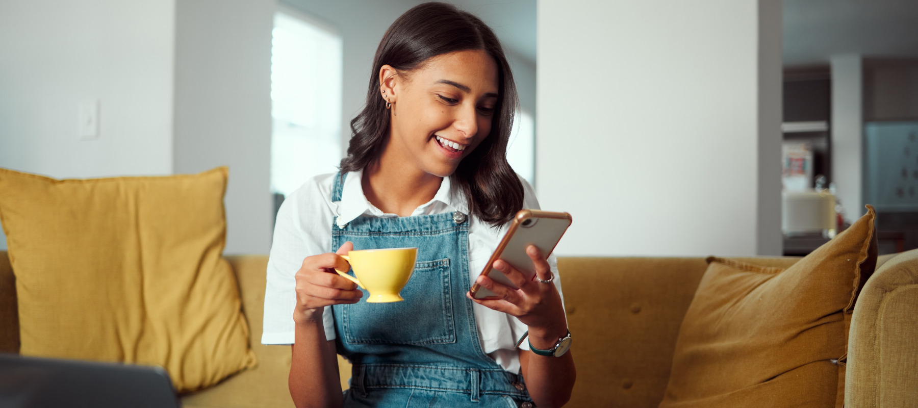 Gen Z homeowner scrolls on social media or e-commerce site on her couch.