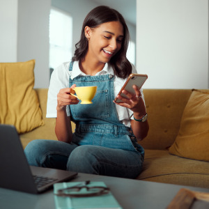 Gen Z homeowner scrolls on social media or e-commerce site on her couch.