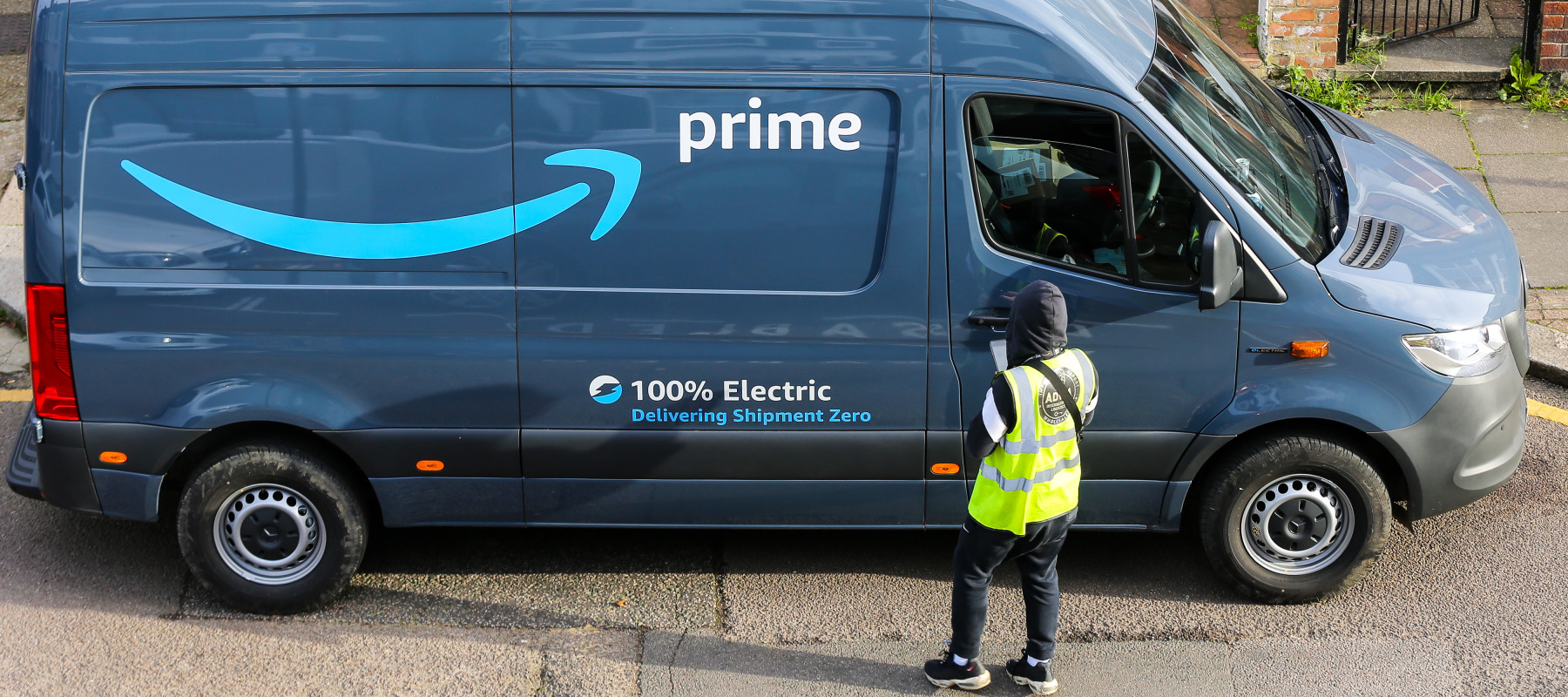 An Amazon delivery driver standing in front of their company delivery van.