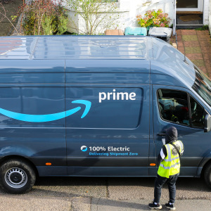 An Amazon delivery driver standing in front of their company delivery van.