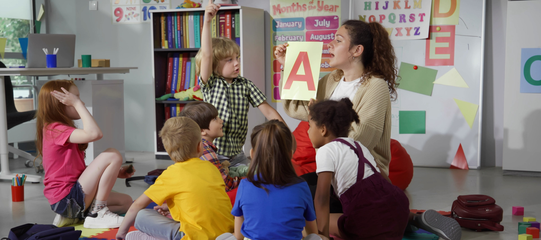 A childcare worker teaches a group of young kids.