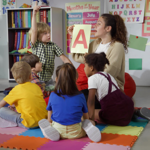 A childcare worker teaches a group of young kids.