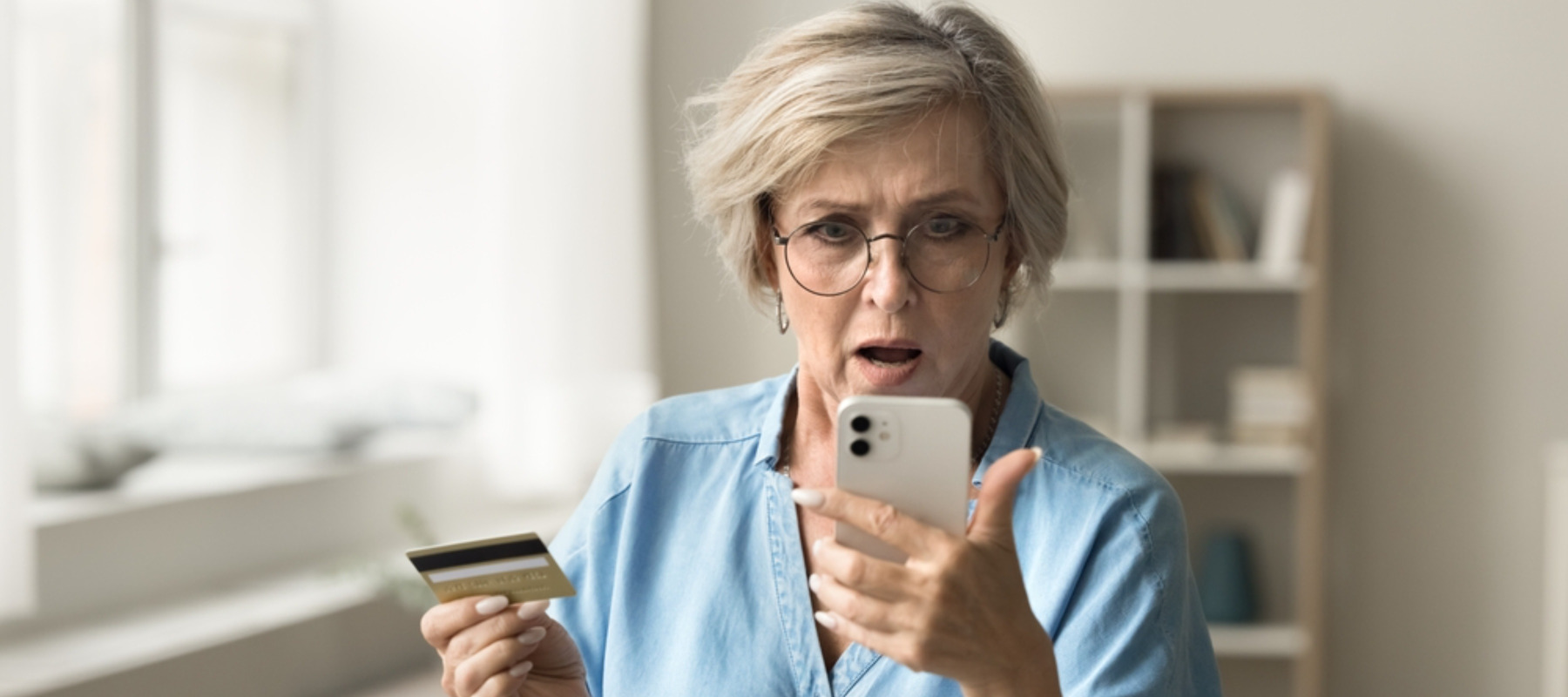 Photo of a woman looking upset and holding a credit card and phone