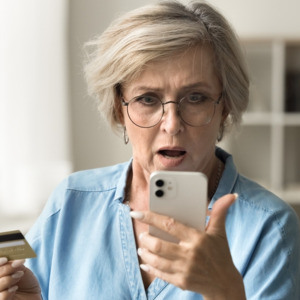 Photo of a woman looking upset and holding a credit card and phone