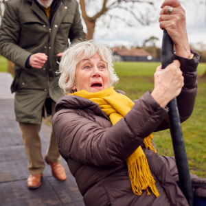 Senior woman playfully rides on a zipline at the park.