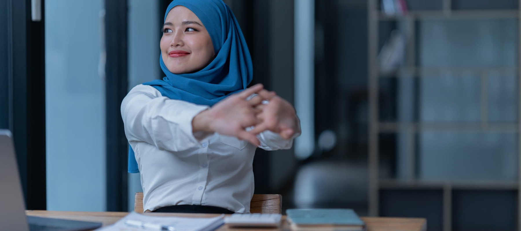 A photo of a woman stretching at her office desk