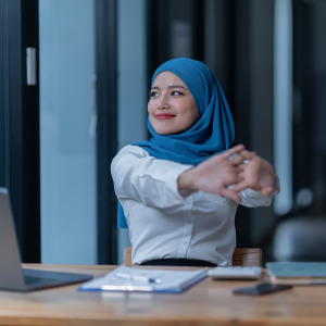 A photo of a woman stretching at her office desk