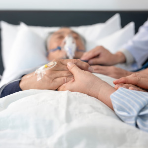 A photo of a man in a hospital bed holding loved ones' hands