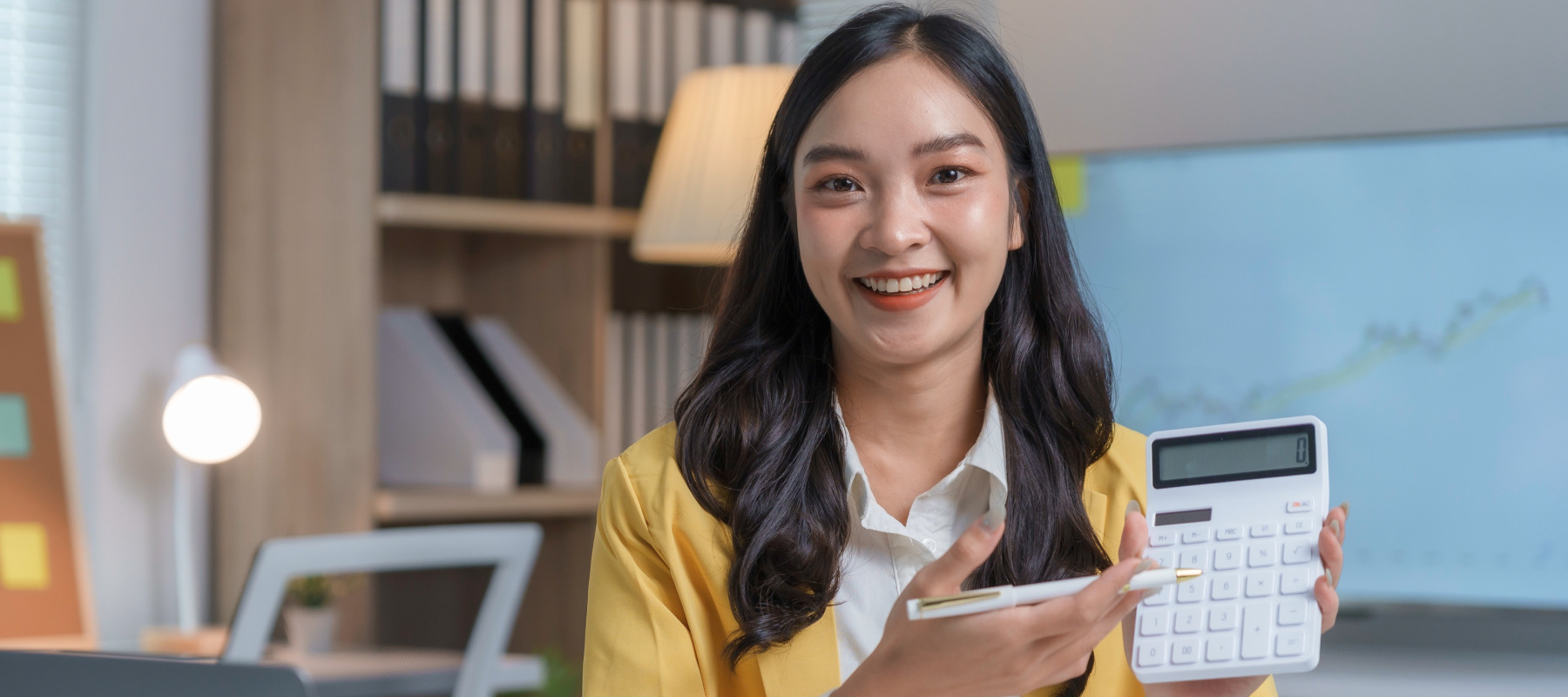 Photo of a smiling woman with a calculator