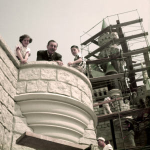 Walt Disney with two children as they look over a ledge during a tour of his Disneyland theme park, which officially opened several months later in March 1955.