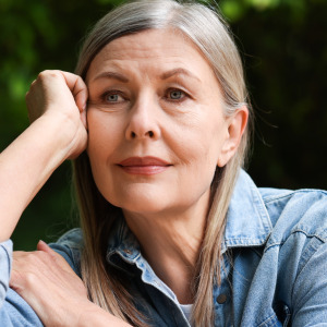 Photo of a pensive older woman sitting on a bench