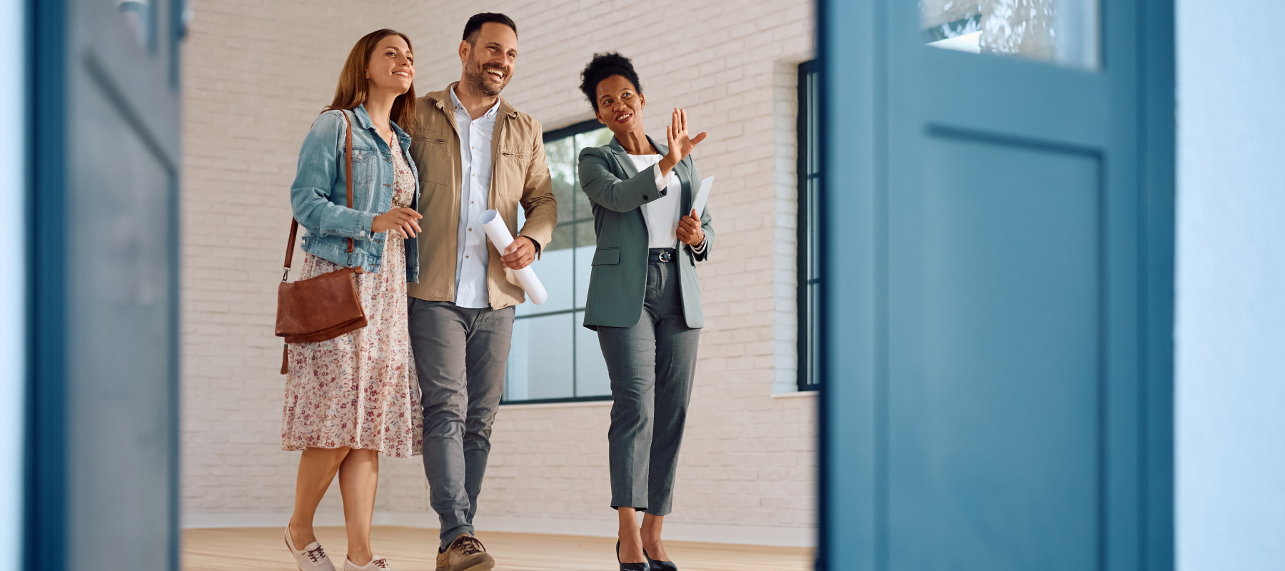 A real estate agent leads a young couple through an open house showing.