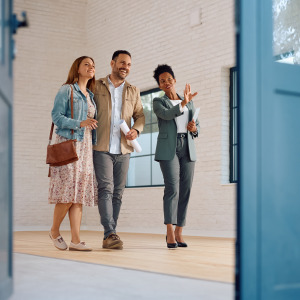 A real estate agent leads a young couple through an open house showing.