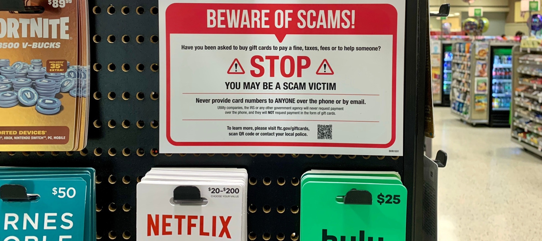 Warning sign for gift card scams next to gift cards for sale