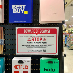 Warning sign for gift card scams next to gift cards for sale
