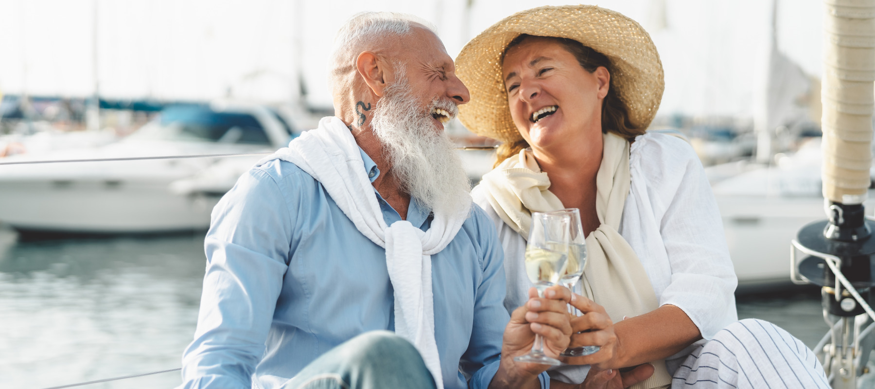 Retired couple toasting champagne on sailboat vacation.