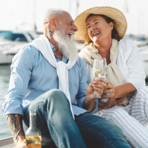 Retired couple toasting champagne on sailboat vacation.