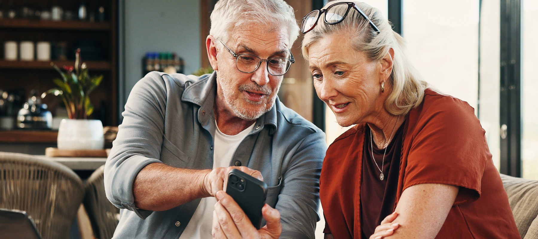 Older couple reviewing information on their laptop and a smarthphone.