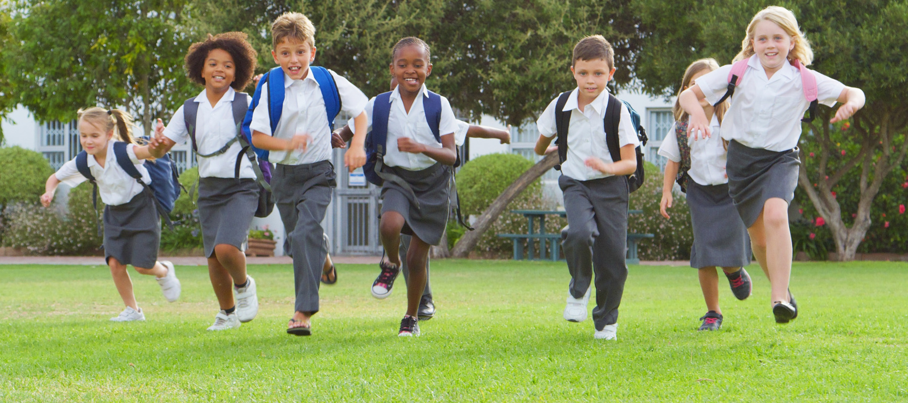 A group of young private school students running together.
