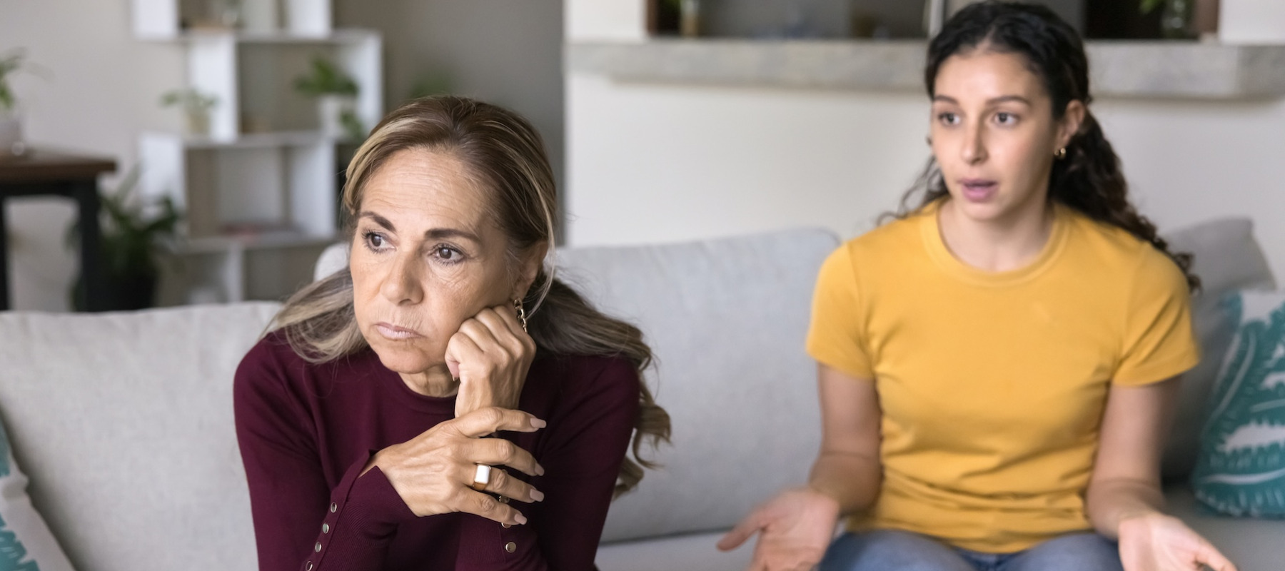 Mother and daughter arguing on couch.