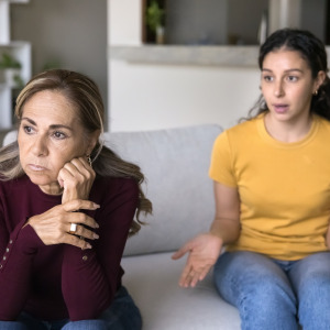 Mother and daughter arguing on couch.