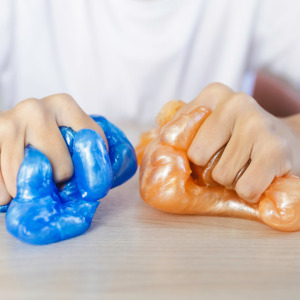 A photo of a man squishing blue and orange slime