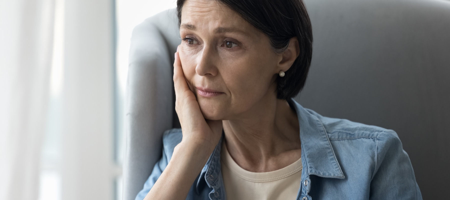 Worried woman sitting by window.