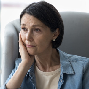 Worried woman sitting by window.