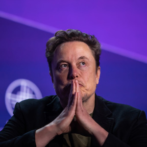 Elon Musk sits in a chair looking pensive.