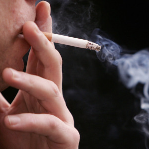 An unidentified man smokes a cigarette in the street outside his office.