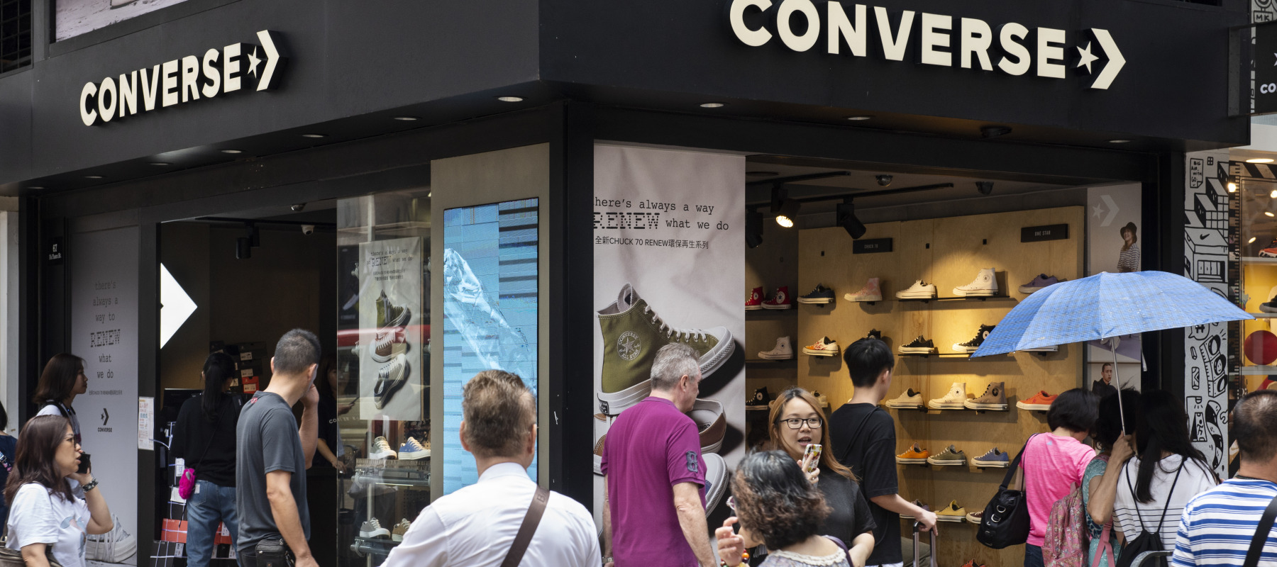 Shoppers are captured walking past a Converse shoe store.