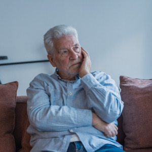 Stressed older man sitting on the couch.