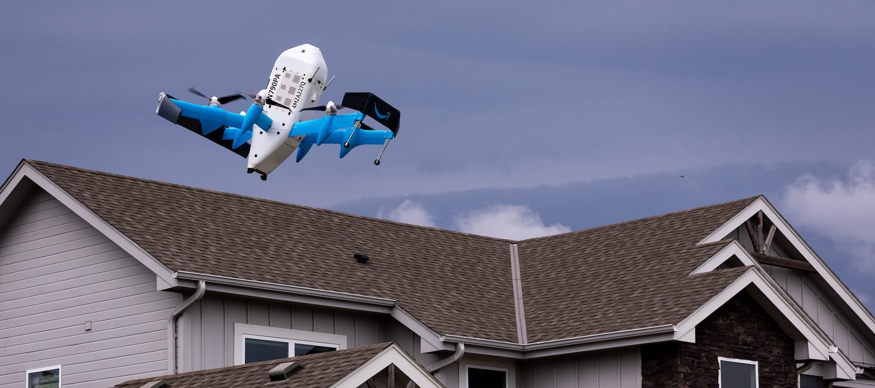 Amazon delivery drone flying above houses.